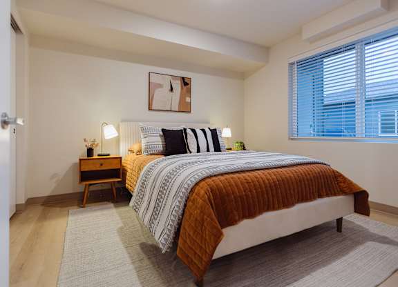A bedroom with a bed, nightstand, and window.