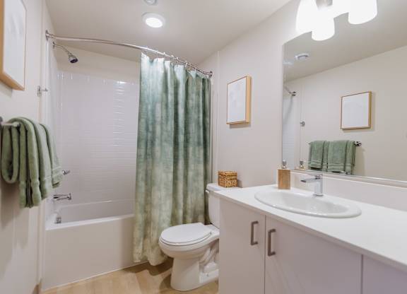 A white bathroom with a toilet, sink, and shower.