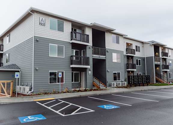 A parking lot in front of apartment building with a handicap parking space.