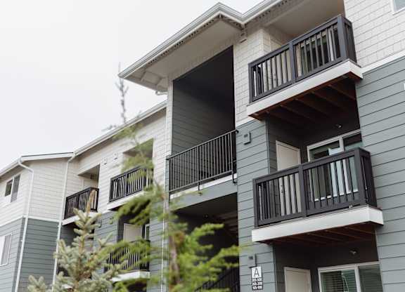 A grey apartment building with balconies and windows.