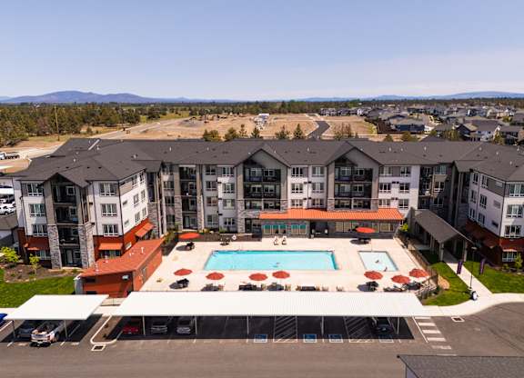 A large apartment complex with a swimming pool in the foreground.