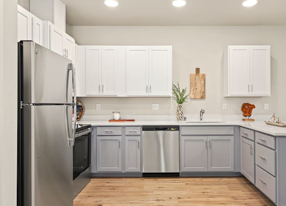 A kitchen with white cabinets and a wooden cutting board on the wall.