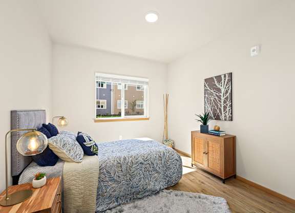 A bedroom with a bed, nightstand, and a window overlooking a cityscape.