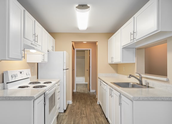 a kitchen with white cabinets and white appliances and a sink