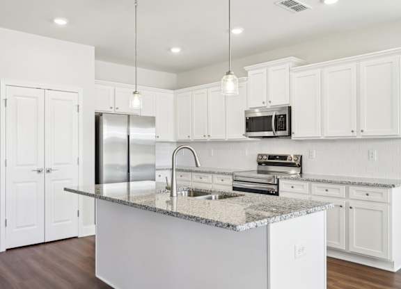 A kitchen with white cabinets and a granite countertop.