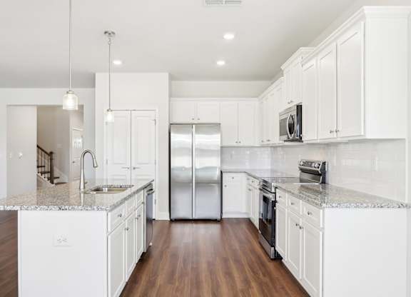 A modern kitchen with white cabinets and a granite countertop.