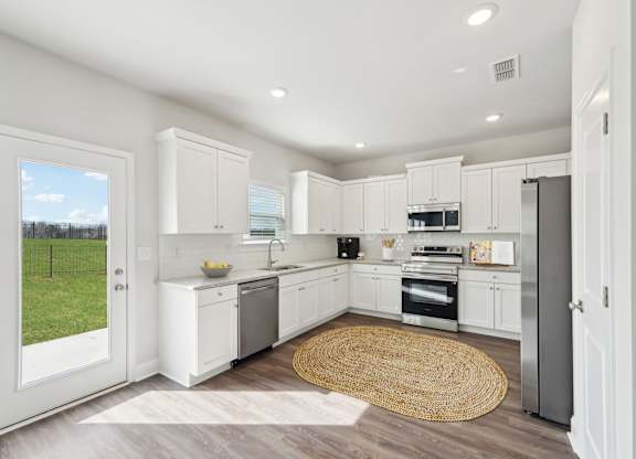 A modern kitchen with white cabinets and stainless steel appliances.