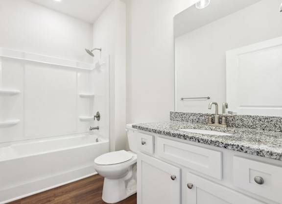 A white bathroom with a marble countertop and a white toilet.