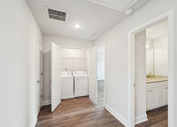 A white bathroom with a wooden floor and a white door.