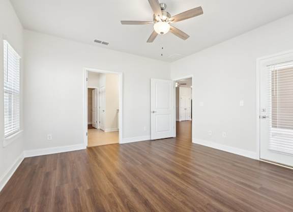 A room with a ceiling fan and wooden flooring.
