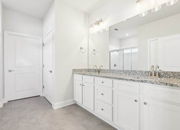 A bathroom with a white vanity and a white door.