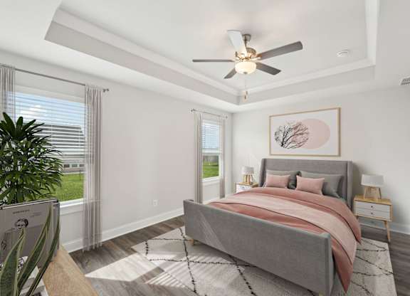 Primary bedroom with trayed ceiling and fan
