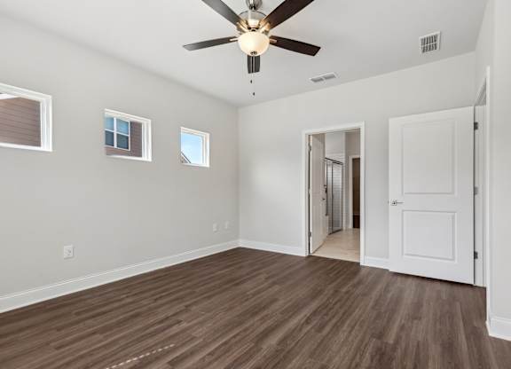 A room with a ceiling fan and wooden flooring.