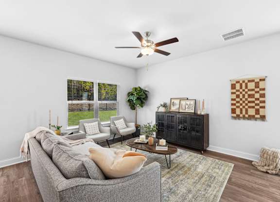 A living room with a grey couch, a coffee table, and a ceiling fan.