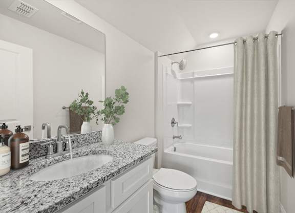 A white bathroom with a marble countertop and a white toilet.