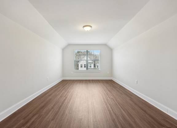 A room with wooden flooring and white walls.