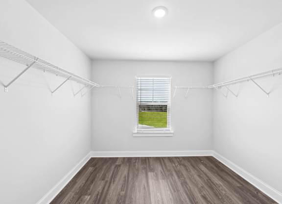 Empty room with a window and a view of a green field outside.