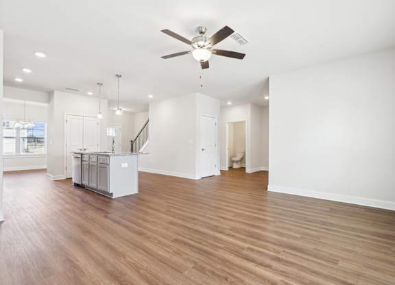 A spacious room with a ceiling fan and wooden flooring.