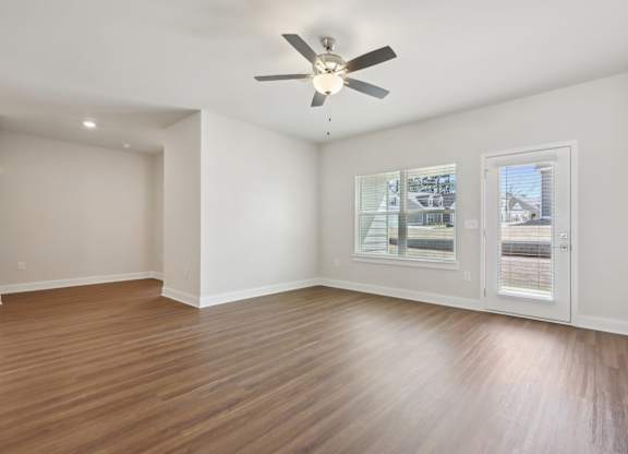 A room with a ceiling fan and a window overlooking a street.