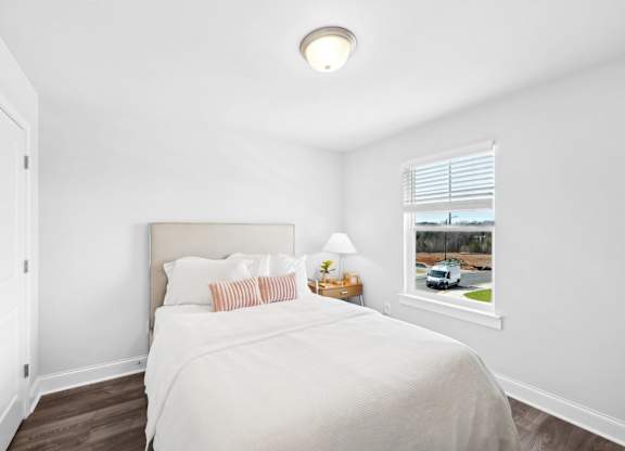 A bedroom with a bed, nightstand, and window.