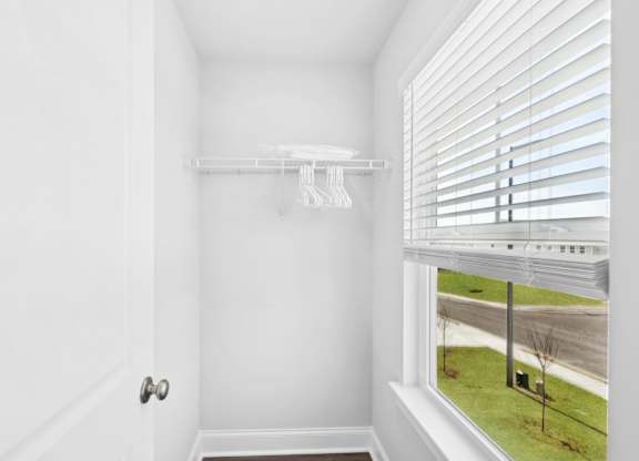 A white door with a white wall and a window with blinds.