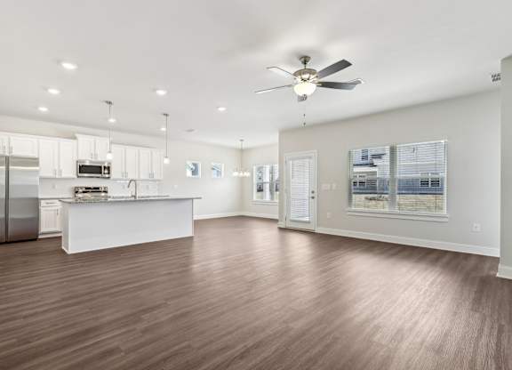 A spacious kitchen with a refrigerator, sink, and a ceiling fan.