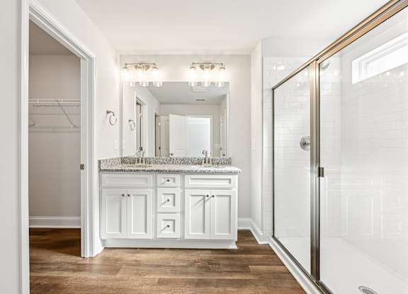 Primary bathroom with double vanity, walk-in shower and walk-in closet.