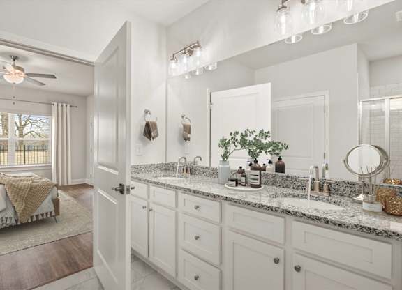 A bathroom with a large mirror, a sink, and a bedroom with a window.