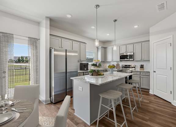 A modern kitchen showcasing a granite countertop island with bar seating and premium stainless steel appliances.