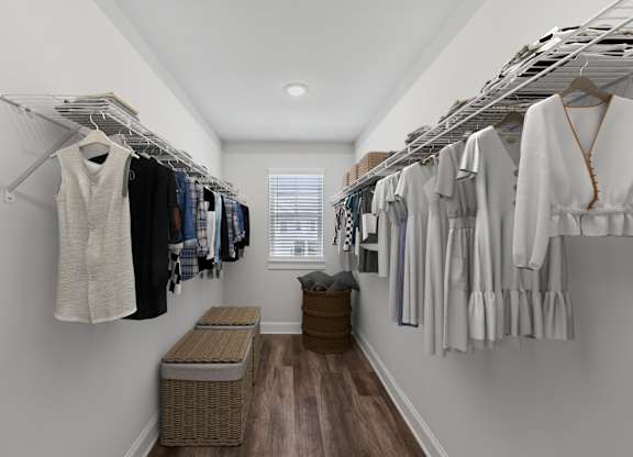 Primary suite with a full walk in closet featuring custom racks and a stylish bench.
