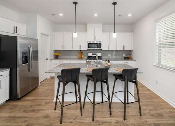View of the kitchen and entry hallway. Offering bar seating, plenty of cabinet space and granite countertops.