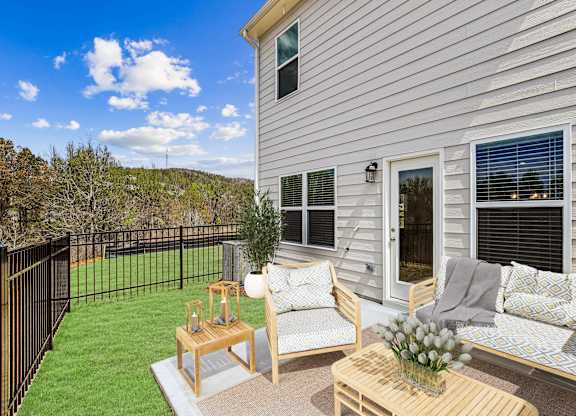 a patio with two chairs and a table in front of a house