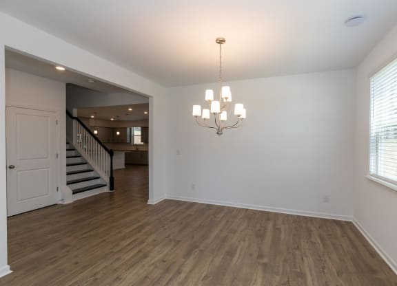 a living room with white walls and wooden floors and a staircase