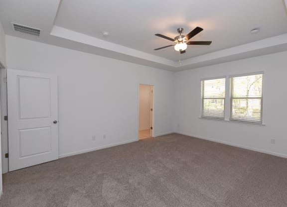 an empty living room with a ceiling fan and a window