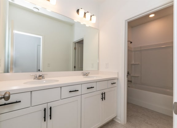 a white bathroom with two sinks and a mirror
