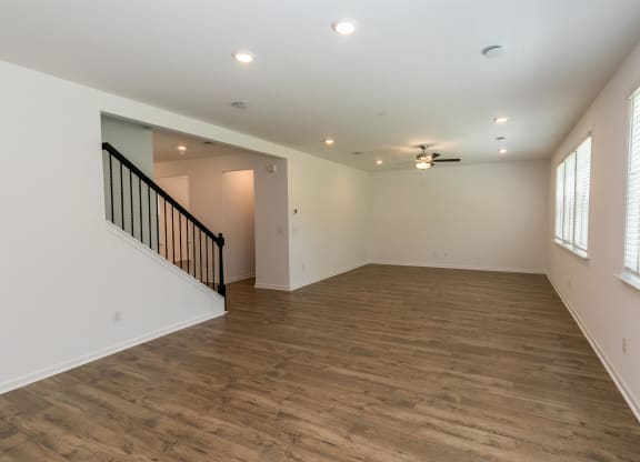 an empty living room with a hard wood floor and a ceiling fan