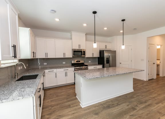 a kitchen with white cabinets and a marble counter top
