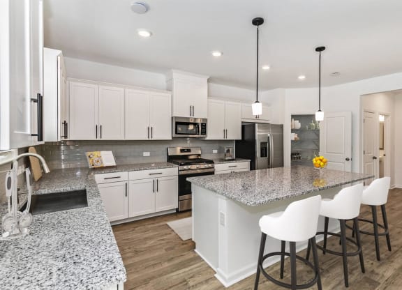 a kitchen with white cabinets and a marble counter top