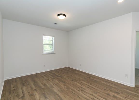 an empty living room with white walls and wood flooring