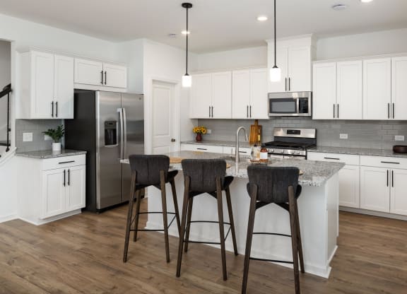 a kitchen with white cabinets and a island with three stools