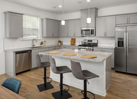 a kitchen with stainless steel appliances and an island with two chairs