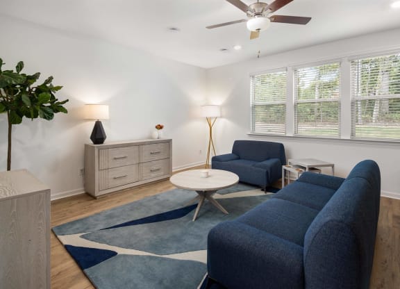 a living room with blue furniture and a ceiling fan