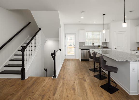 a living room with a staircase and a kitchen