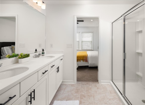 a white bathroom with two sinks and a shower