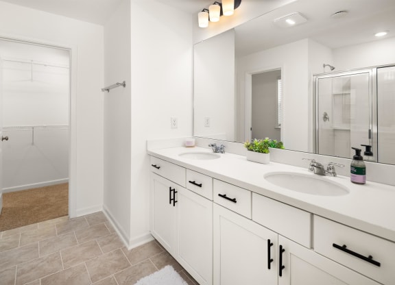 a white bathroom with two sinks and a shower