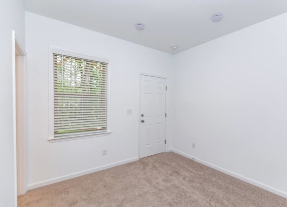 a bedroom with white walls and a window and a door