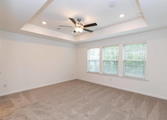 an empty living room with a ceiling fan and a window