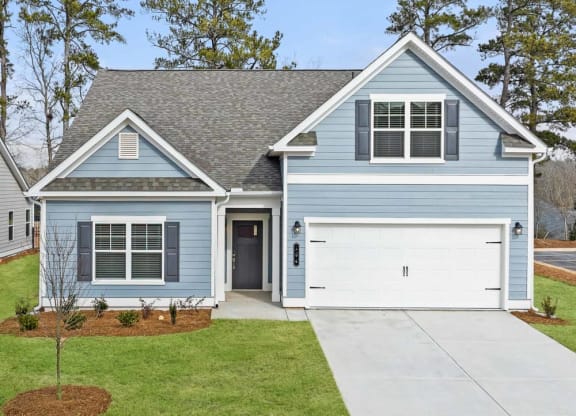 the front of a blue house with a white garage door