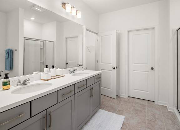 Primary bathroom with double vanity and walk-in shower .