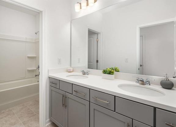 A bathroom with a white countertop and a grey cabinet.